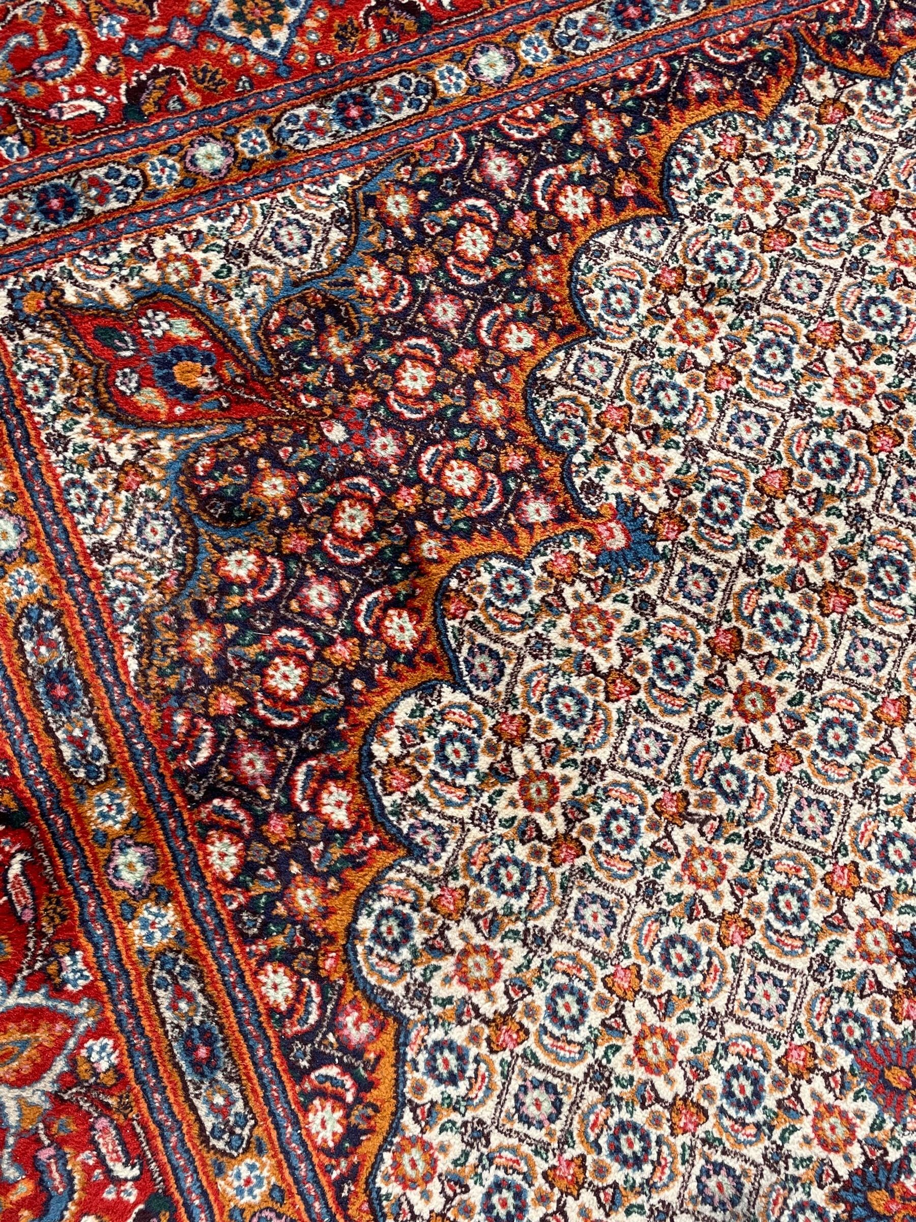 Persian Bidjar ivory and indigo ground rug, large central rosette medallion surrounded by floral herati motifs, crimson ground border decorated with repeating palmettes, within guard stripes decorated with small flower head motifs 