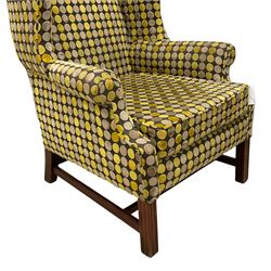 Georgian design mahogany framed wingback armchair, upholstered in spotted fabric in shades of grey and green, on moulded square supports united by stretchers 