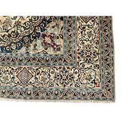 Persian Nain ivory ground carpet, central indigo medallion, the busy floral field decorated with scrolling vines and flower heads in shades of blue, beige, and red, wide guarded border with repeating palmettes and foliate motifs