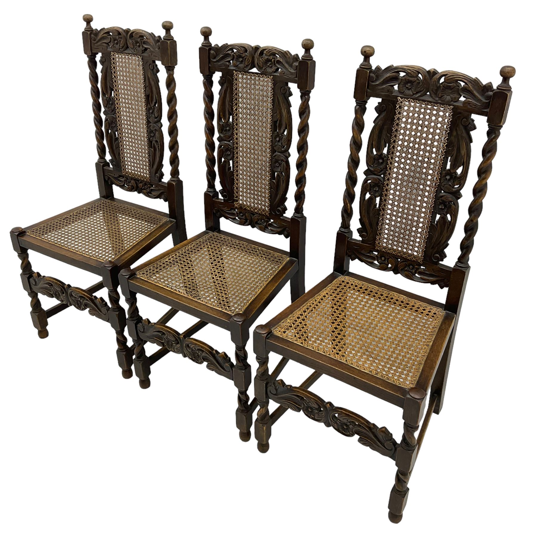 Set of seven (5+2) 19th century Carolean design oak dining chairs, scroll leaf and flower head carved cresting rail over spiral turned uprights and cane work back, the cane work seat on spiral turned supports united by plain stretchers, scrolled leaf carved middle rail 