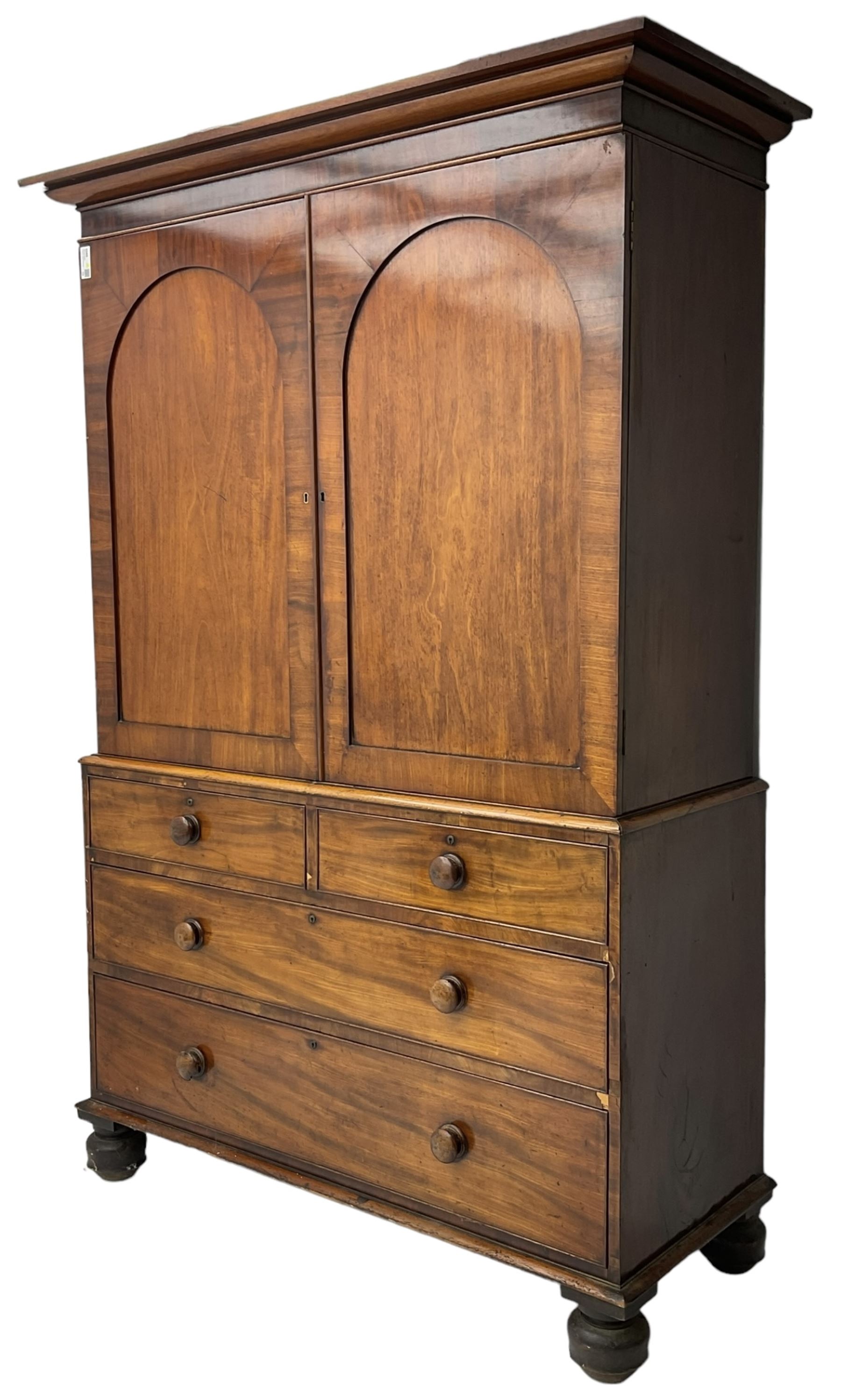 Victorian figured mahogany linen-press, projecting moulded cornice over two arch panelled doors, fitted with two short and two long cock-beaded drawers, on turned feet