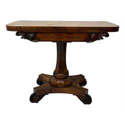 Early Victorian rosewood card table, rectangular foldover swivel top with rounded corners, red baize-lined surface, frieze adorned with carved foliate motifs, supported by a central octagonal waisted column on shaped quatrefoil base, terminating in scrolled feet with concealed metal castors