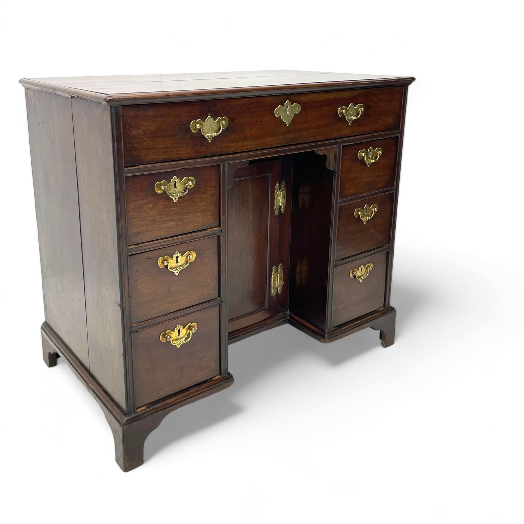 George III mahogany kneehole desk, moulded rectangular top over one long drawer, six short drawers and recessed panelled cupboard, cock-bead moulded frame, fitted with shaped brass handle plates with engraved decoration, on bracket feet 