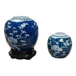 Two blue and white ginger jars in prunus pattern, one upon a carved wooden base 