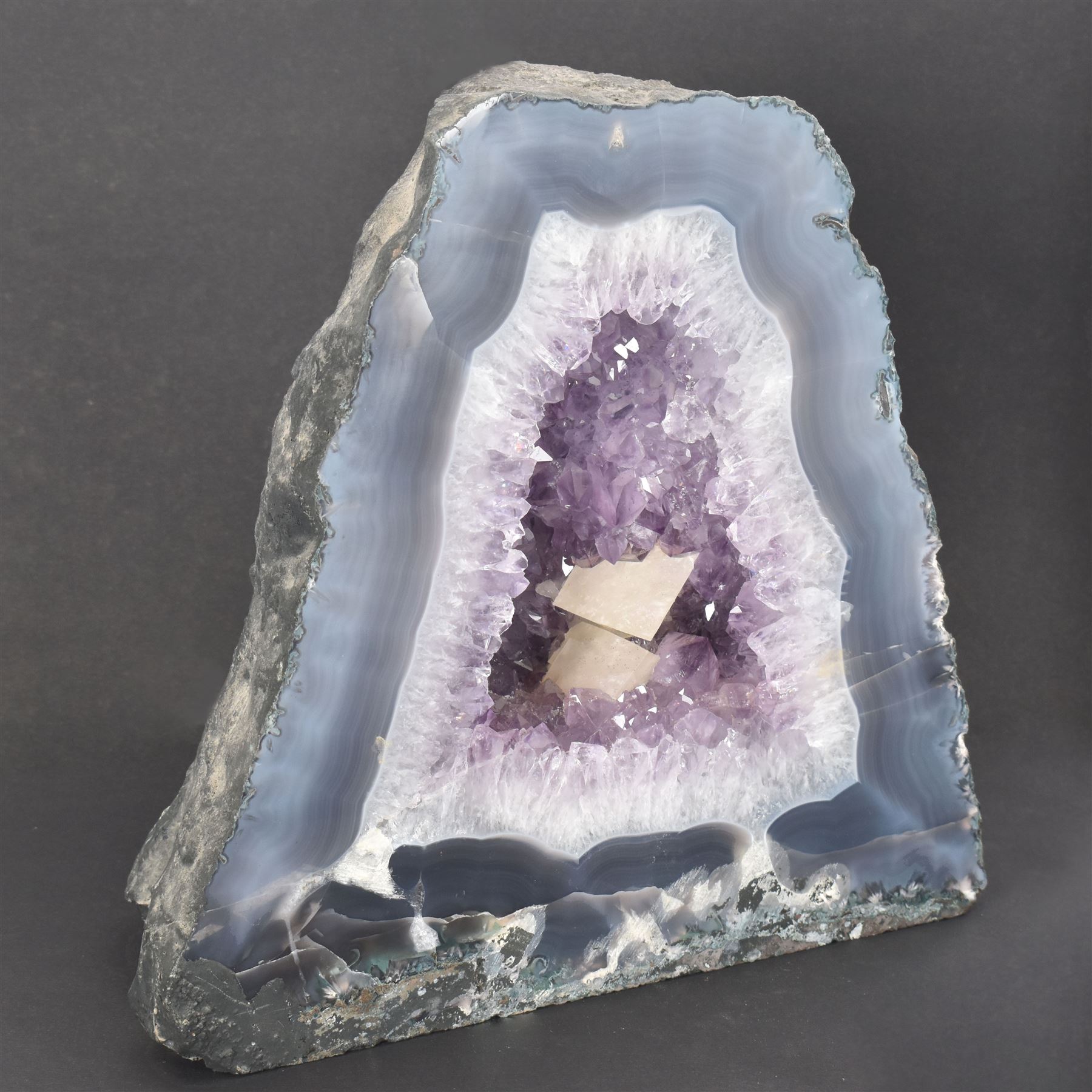 Amethyst crystal ‘cathedral’ geode, free standing with flat base and prepared outer surface, with well-defined crystals of various sizes within the cavern, H25cm, W25cm