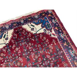 Persian Herati crimson ground rug, the busy field decorated with a central lozenge medallion surrounded by interlocking Herati motifs, the indigo guard band with repeating palmette and stylised plant motifs