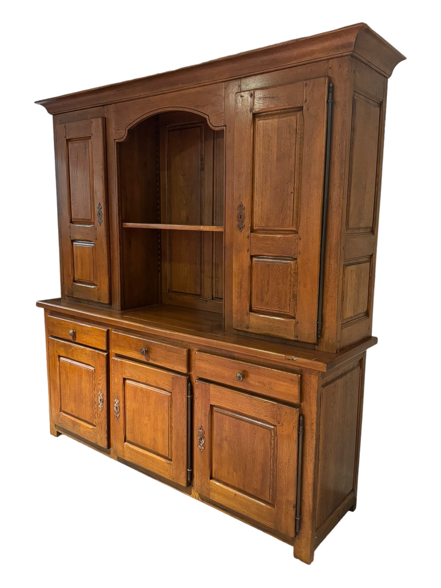 Large 20th century oak dresser, projecting cornice over open arched central section with two shelves, flanked by two panelled cupboards with two shelves, lower section with three drawers above three cupboards, on stile supports 