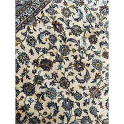 Persian Kashan ivory ground carpet, the busy field decorated with scrolling and interlaced leafy branches and palmettes, trailing branch border with repeating stylised plant motifs, within floral pattern guard stripes 