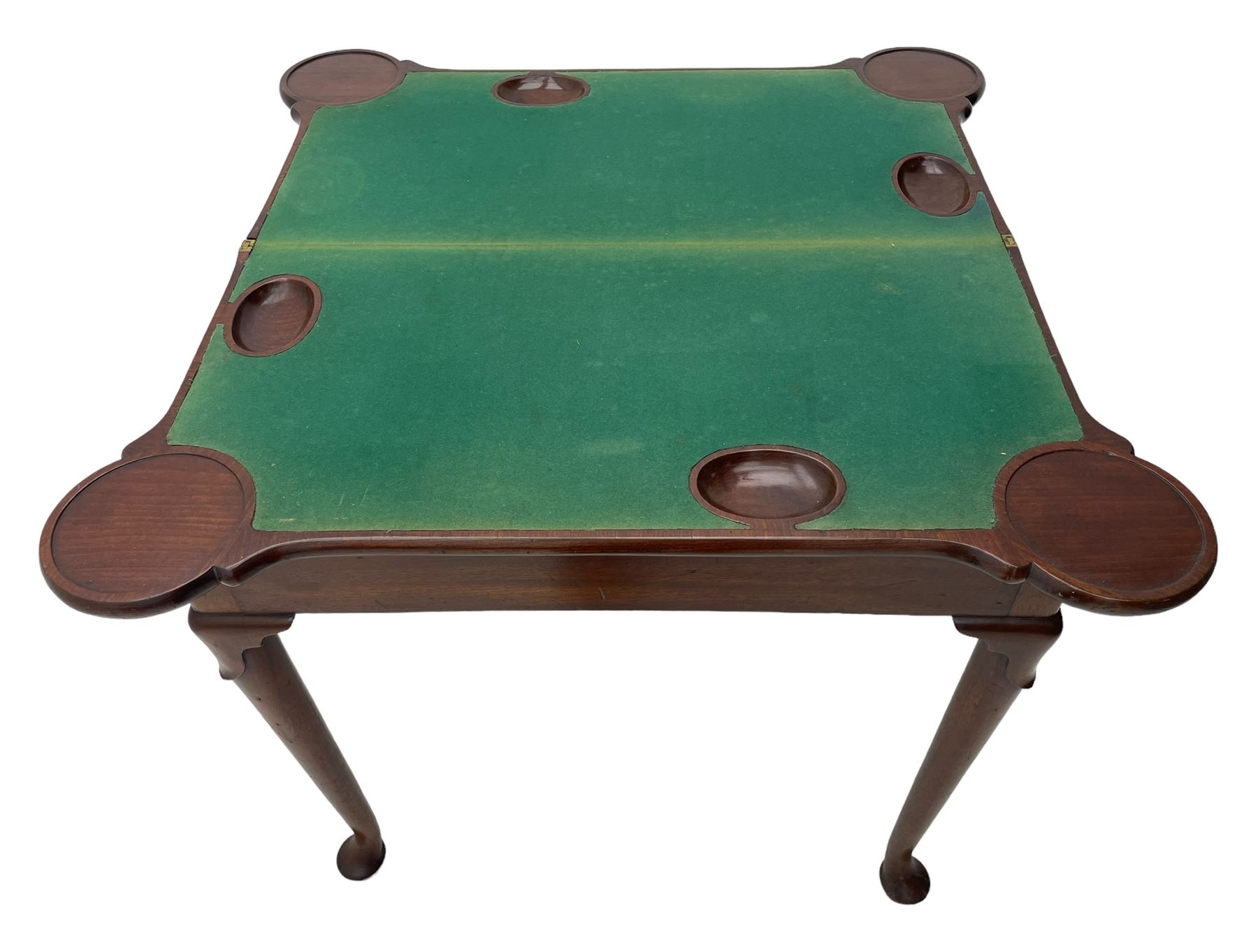 George III mahogany games table, the rectangular fold-over top with extending stepped rounded corners, opening to reveal baize lined interior with sunken counter wells, concertina action base, on lappet cabriole supports