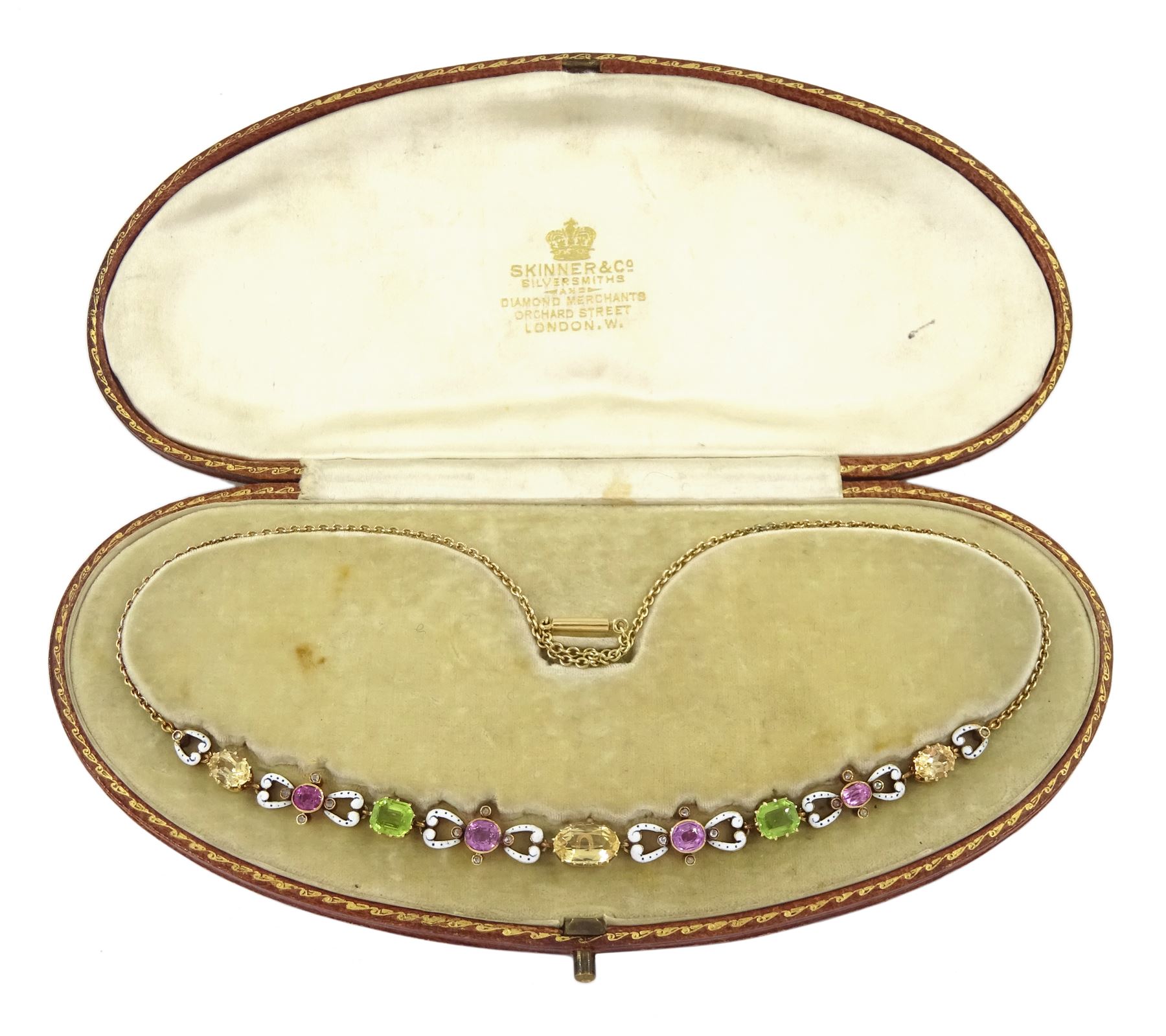 Early 20th century 15ct gold gold orange / yellow / peach topaz, pink tourmaline, pink sapphire peridot and diamond necklace, the pinks stones each set with four rose cut diamonds and spaced by scroll links with white enamel and black dots, to a trace link chain necklace, in fitted silk and velvet lined box by Skinner & Co