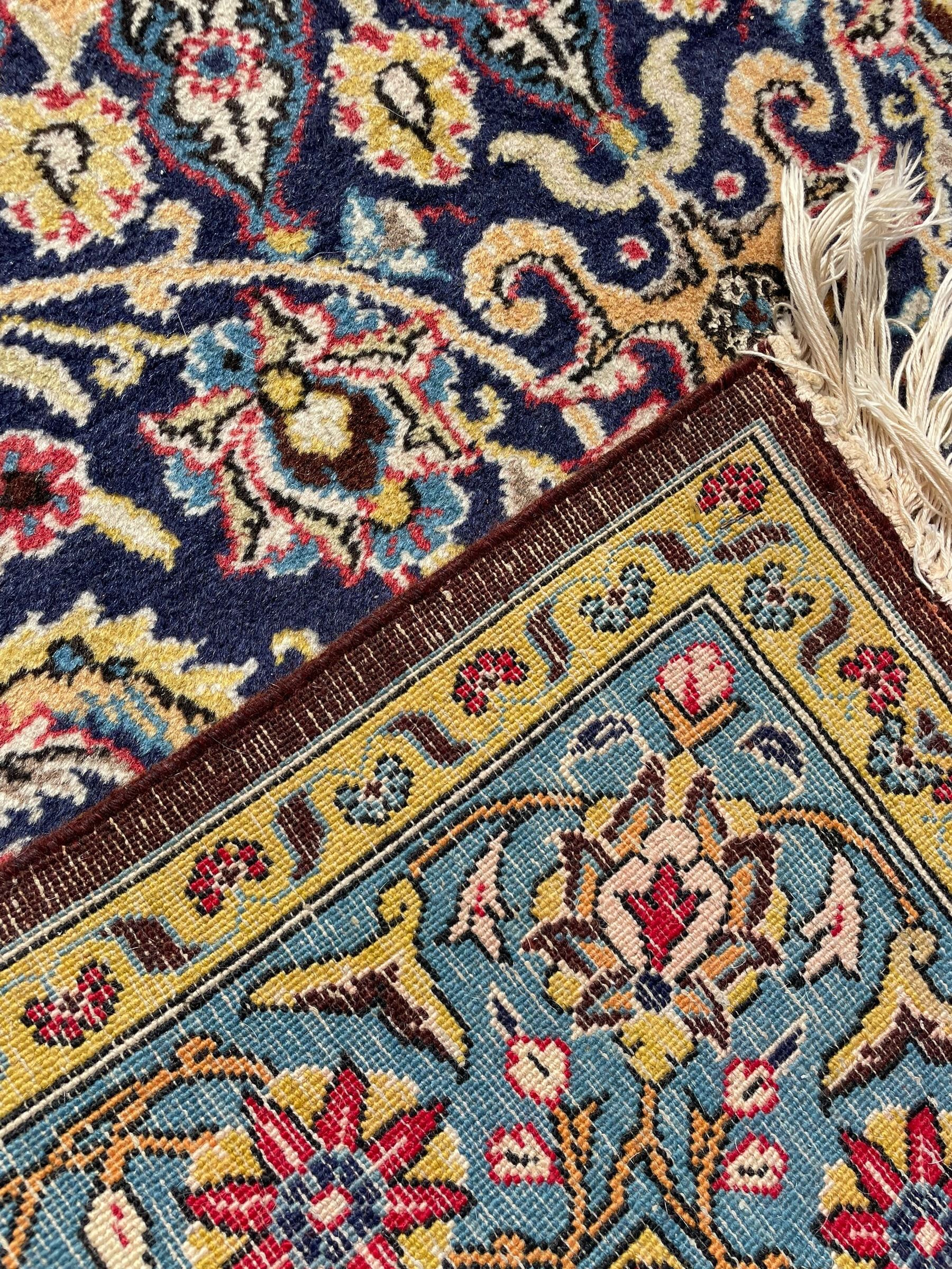 Persian indigo ground rug, overall arabesque design, central multi-point medallion surrounded by scrolling leafy branches and palmettes, the border decorated with repeating stylised plant motifs within guard stripes 