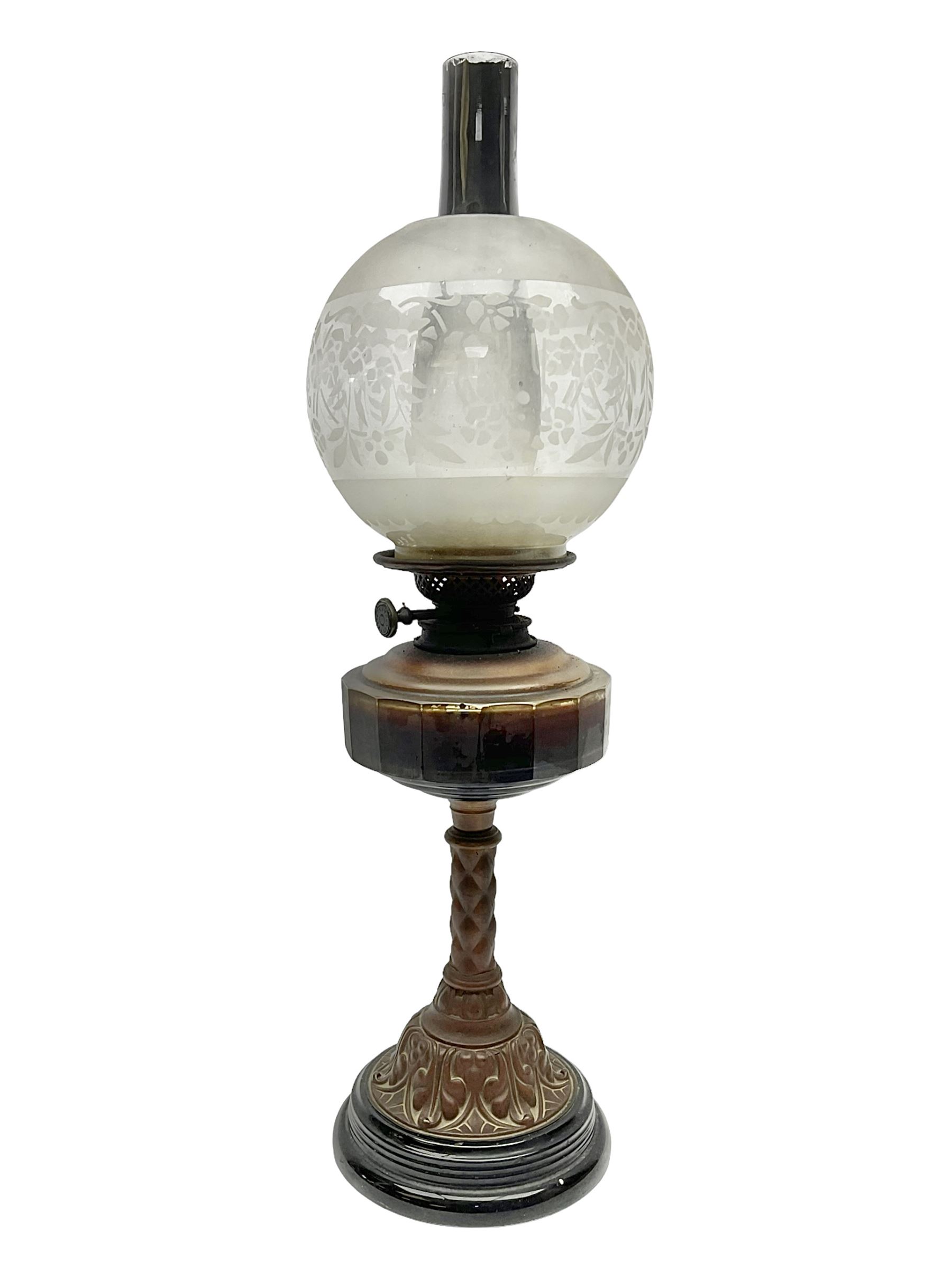 Victorian oil lamp, the faceted reservoir upon embossed copper stem and stepped circular ceramic base, with etched floral glass shade