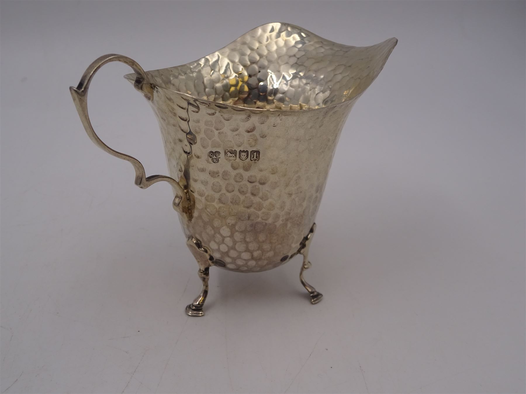 Edwardian silver jug, of helmet form with planished decoration throughout, upon three hoof feet, hallmarked Charles Boyton & Son Ltd, London 1906, H9cm