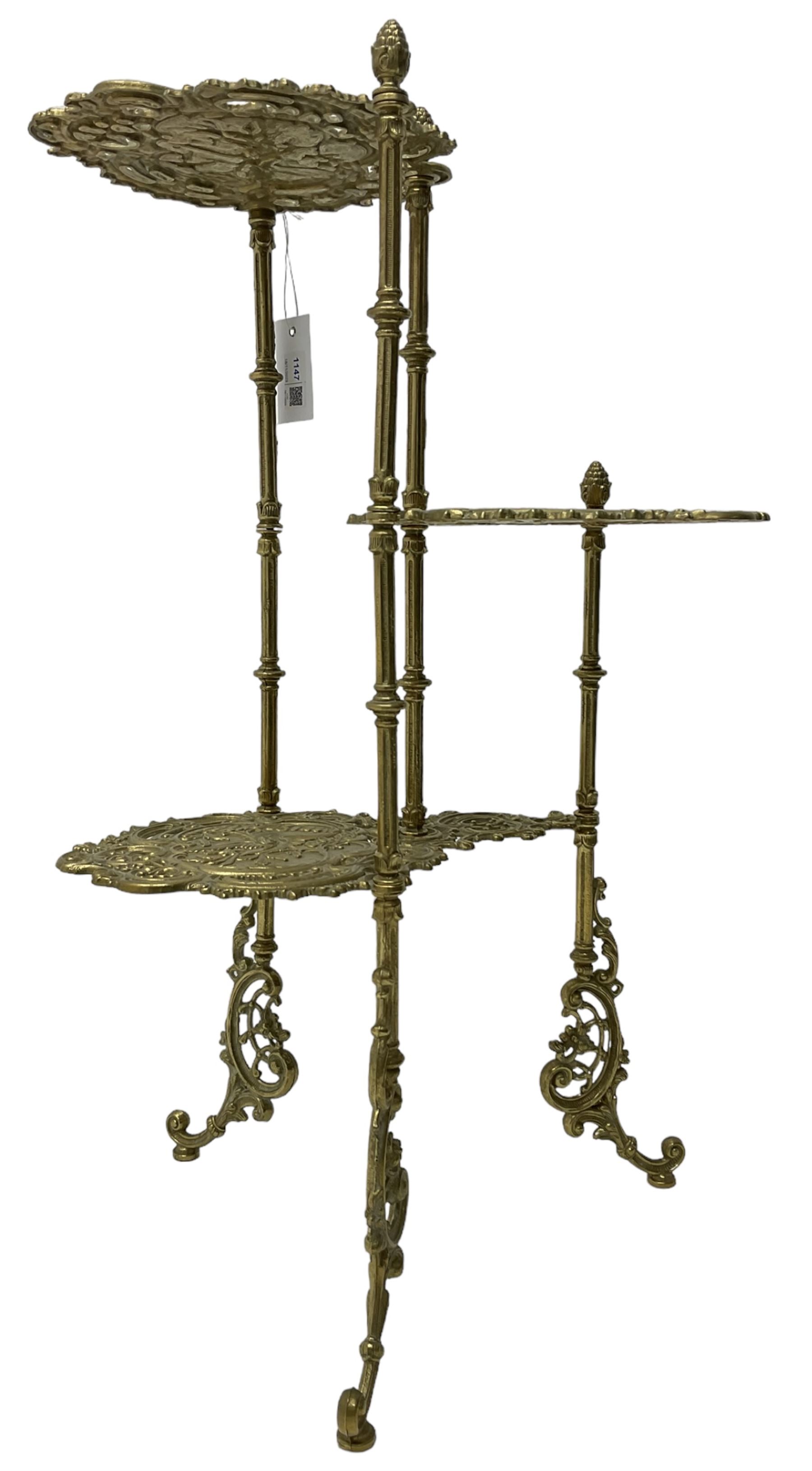 Cast gilt metal three-tier cake stand, each tier decorated with cast foliage scrolls and flower heads with a central bird motif, on turned and fluted supports with splayed C-scroll feet