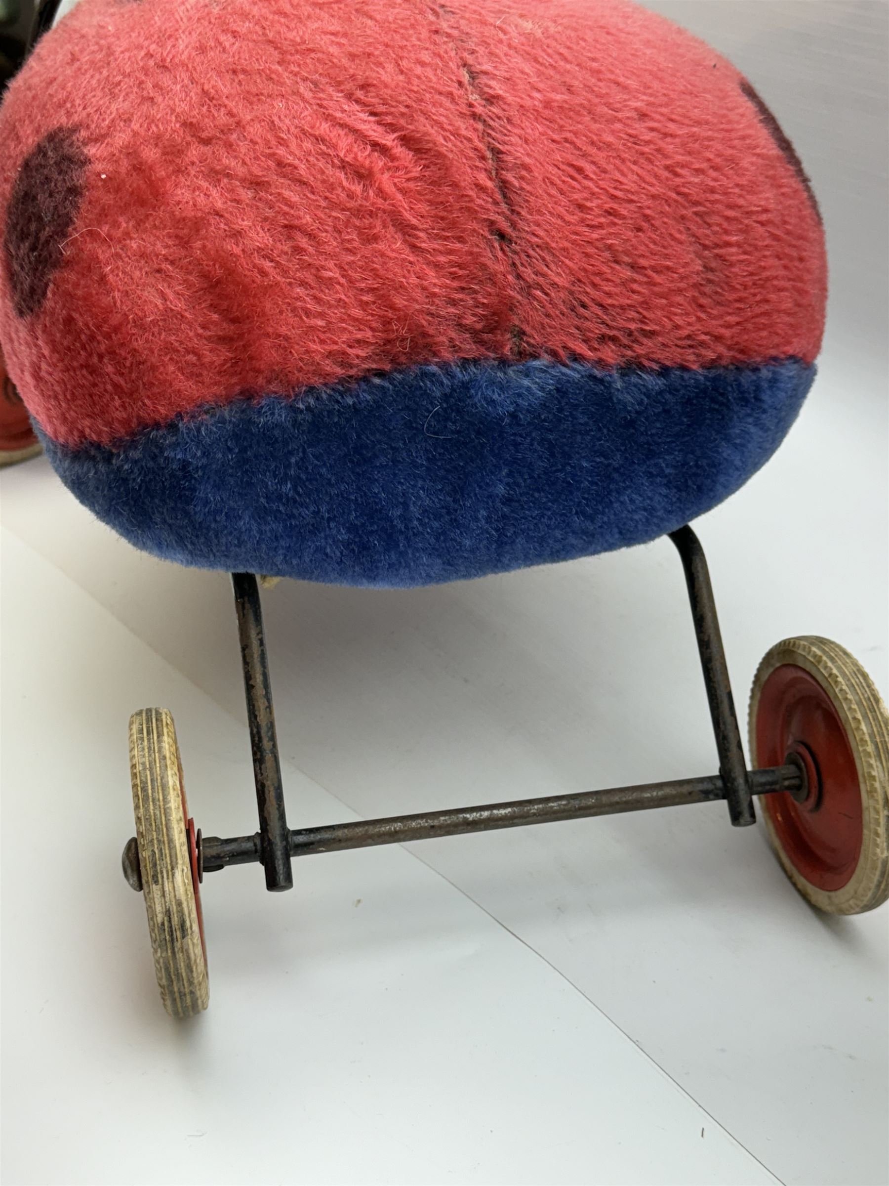 Steiff child's ride on ladybird, circa 1950s, the mohair body with red and black spotted seat, black and white face and blue underbelly, upon a metal frame with rubber and metal wheels, H30cm, W52cm