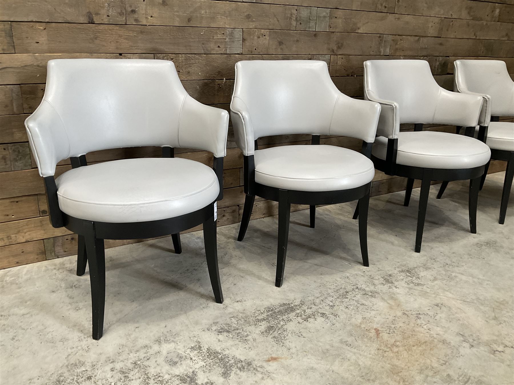 Four ebonised framed tub shaped armchairs, upholstered in grey fabric