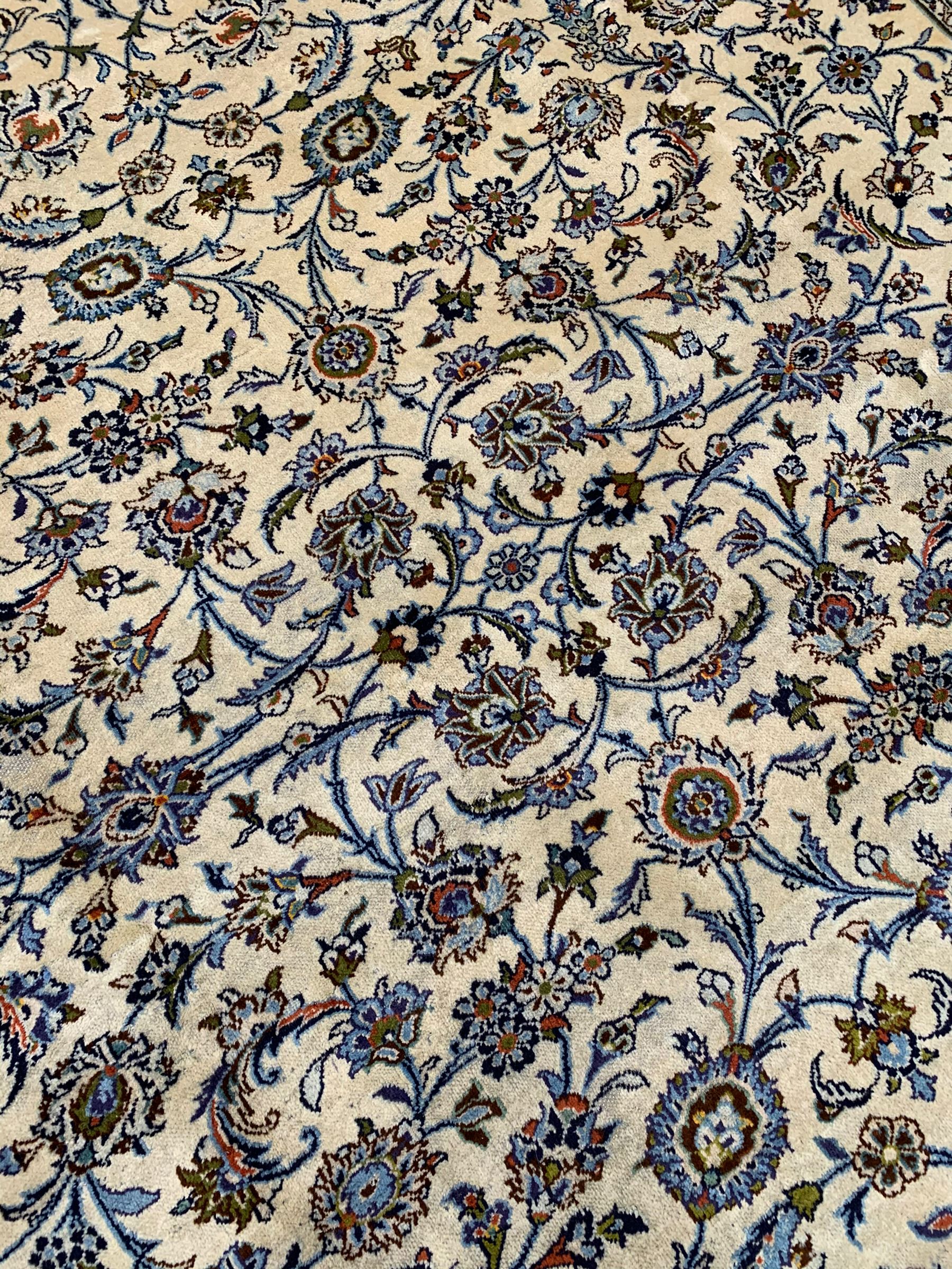 Persian Kashan ivory ground carpet, the field decorated with interlacing leafy branches and stylised plant motifs, repeating border with multiple guards