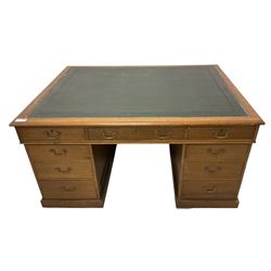 Late 19th century twin pedestal oak partner's desk, rectangular top with inset green leather writing surface, fitted with nine graduating drawers to each side, the rear drawers enclosed by panelled cupboards