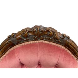 Victorian carved walnut open armchair, foliate carved cresting rail over butted back and sprung seat, upholstered in pink velvet scrolled arm terminals with moulded scrolling vines terminating to cabriole supports and ceramic castors