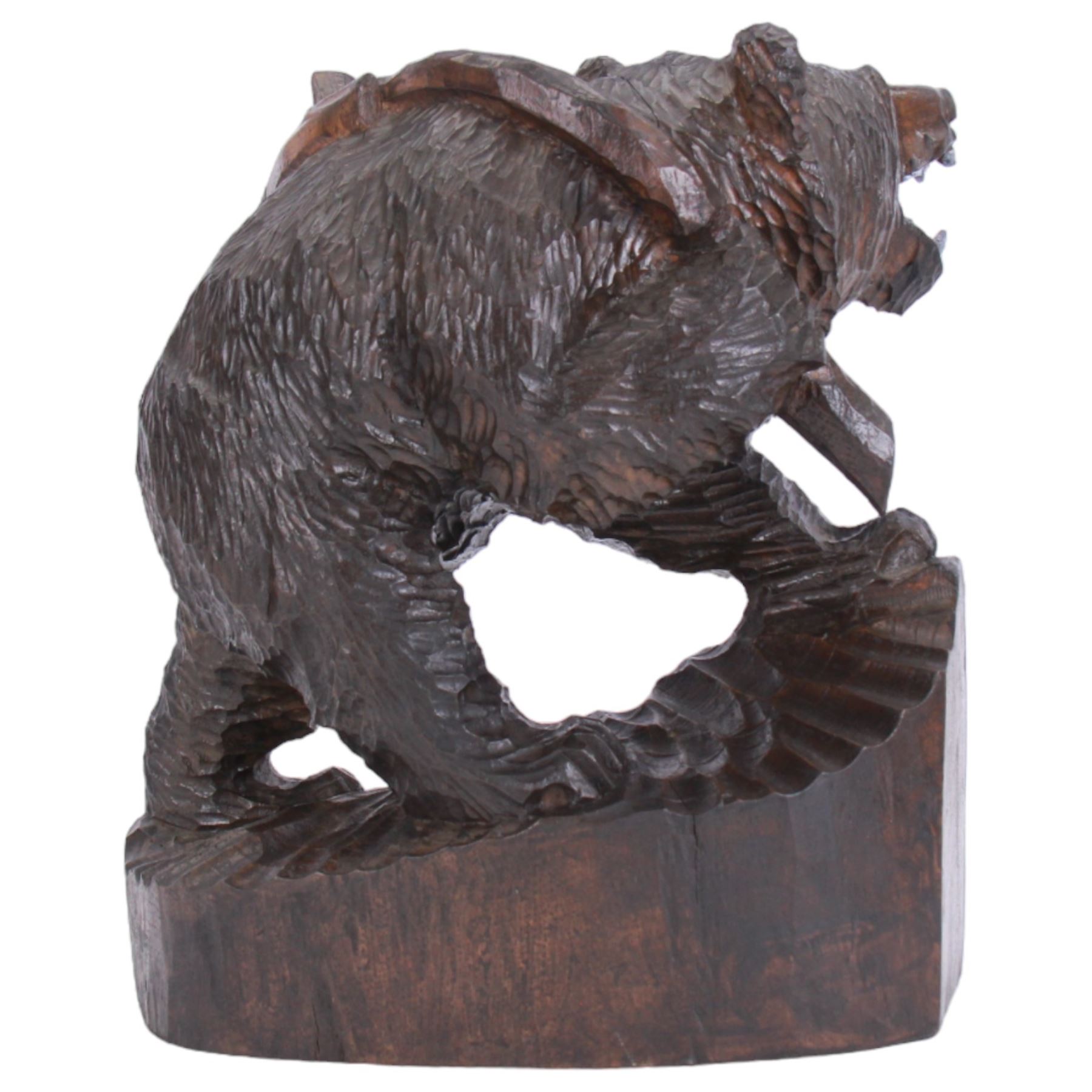 20th century Black Forest carving of a bear carrying a fish upon its back, with open mouth, painted tongue and teeth, and inset glass eyes, stood  upon a naturalistic base, overall H37cm L34cm W18cm