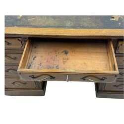 20th century oak twin pedestal desk, rectangular top with inset leather writing surface, fitted with nine drawers with chamfered edges to the raised panels, each with curved brass handles with scroll ends and keyholes, fluted detailing to the top and between the drawers, on moulded plinth base with castors