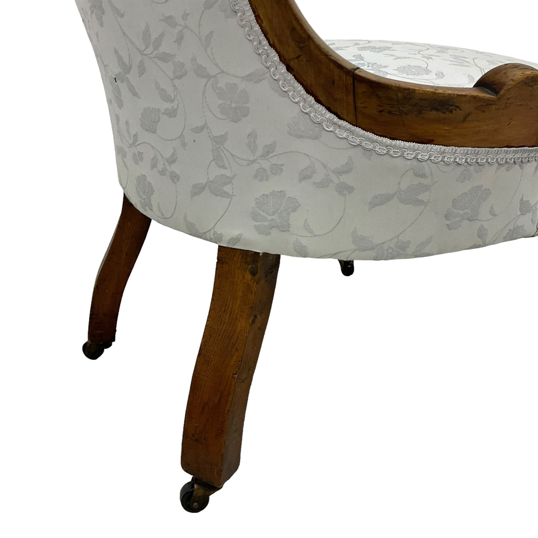 Victorian walnut nursing chair, the curved cresting rail carved with central cartouche and scroll leaves, upholstered in pale blue fabric decorated with trailing floral design, on cabriole front feet 