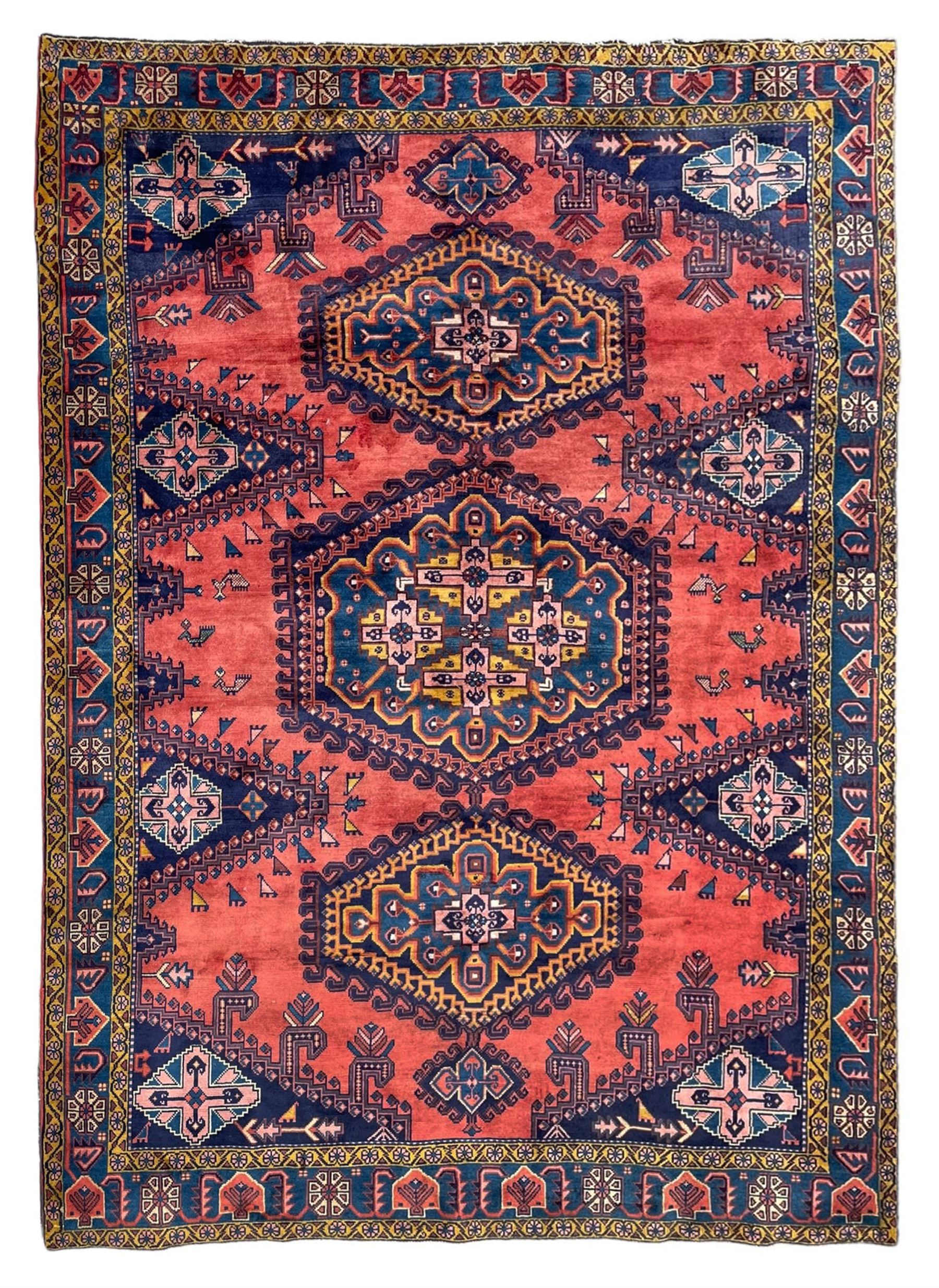 Persian Wiss pale crimson ground rug, three medallions with hooked borders, the field punctured with projecting lozenges, decorated with hac motifs, plain field decorated with stylised bird motifs, the border decorated with rosettes and repeating geometric motifs, within guard stripes 