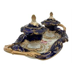 19th century porcelain inkstand, the oblong twin handled base centrally painted with a floral bouquet, flanked by two footed inkwells and covers, with rococo-inspired acanthus moulded borders and handles, pattern no. 2/3339, L26.5cm 