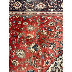 Persian Kashan crimson ground carpet, central shaped pale ground medallion surrounded by interlacing branches and stylised floral motifs, indigo main border with scrolling foliage design, within guard stripes 