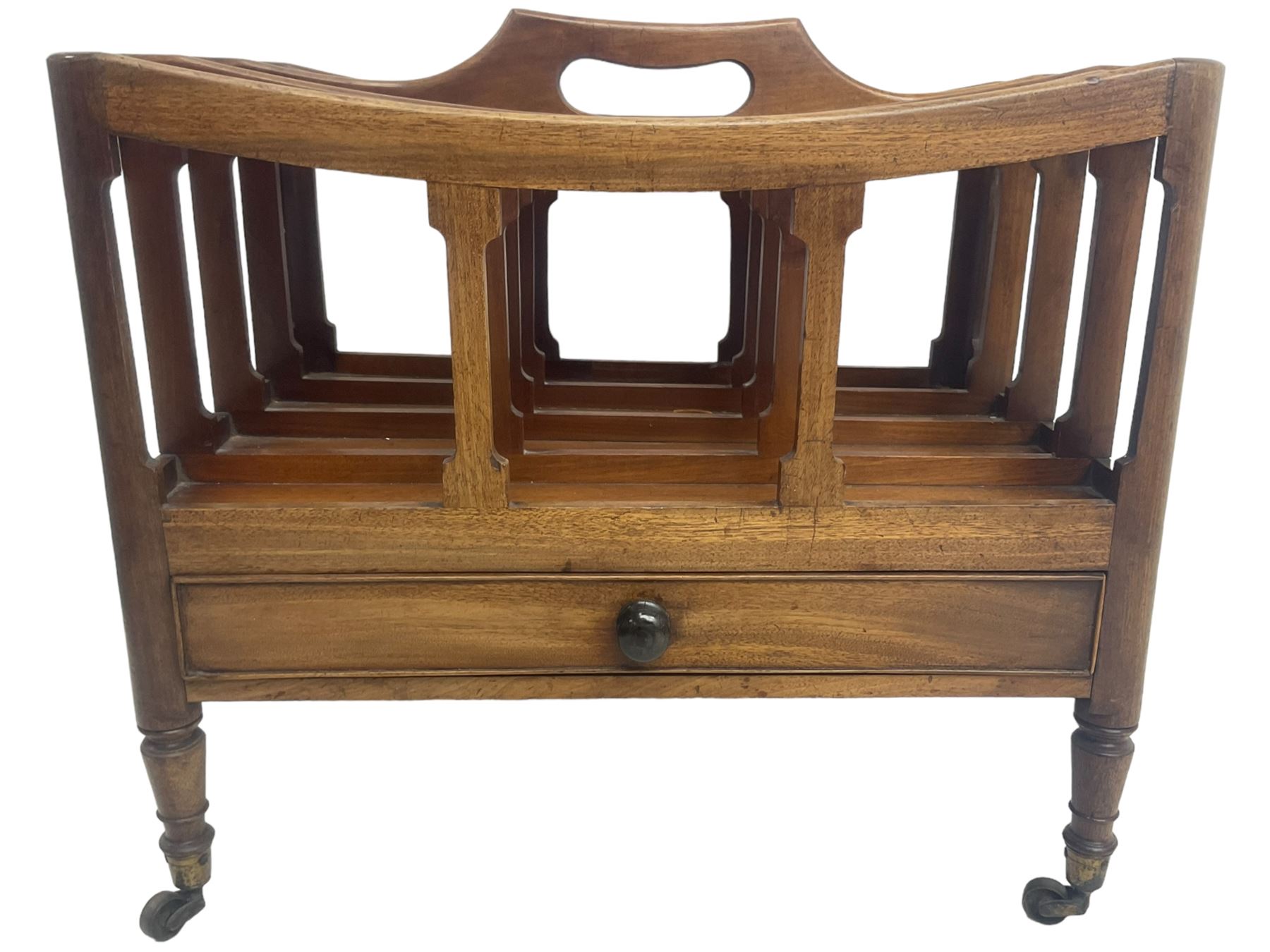 George III mahogany four-division Canterbury, the concave shaped dividers with a central pierced handle, over a single cock-beaded drawer, raised on turned supports terminating in brass cups and castors