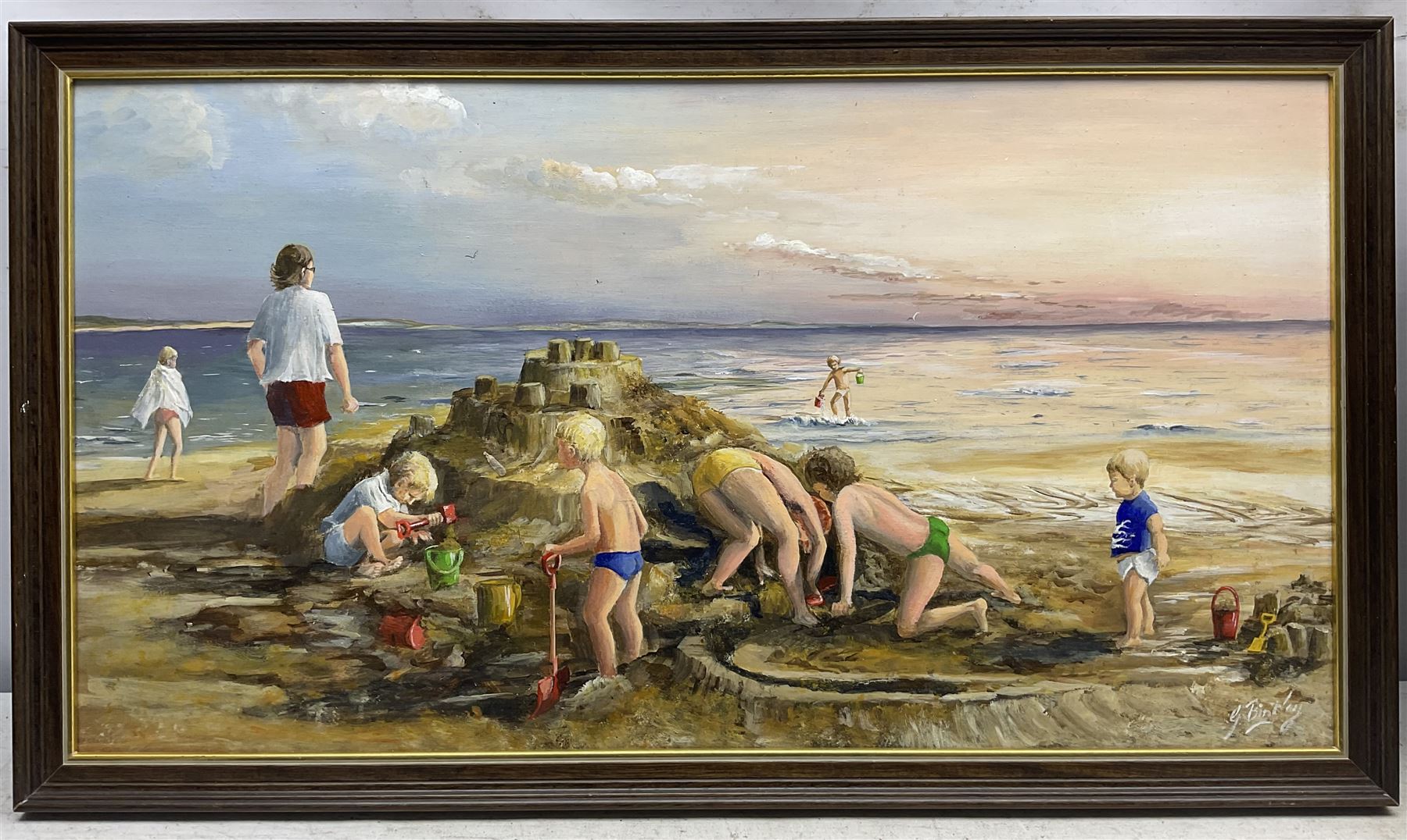 Glenys Bintley (Northern British 20th Century): Children Building a Sandcastle, oil on board signed, artists address label verso 34cm x 64cm