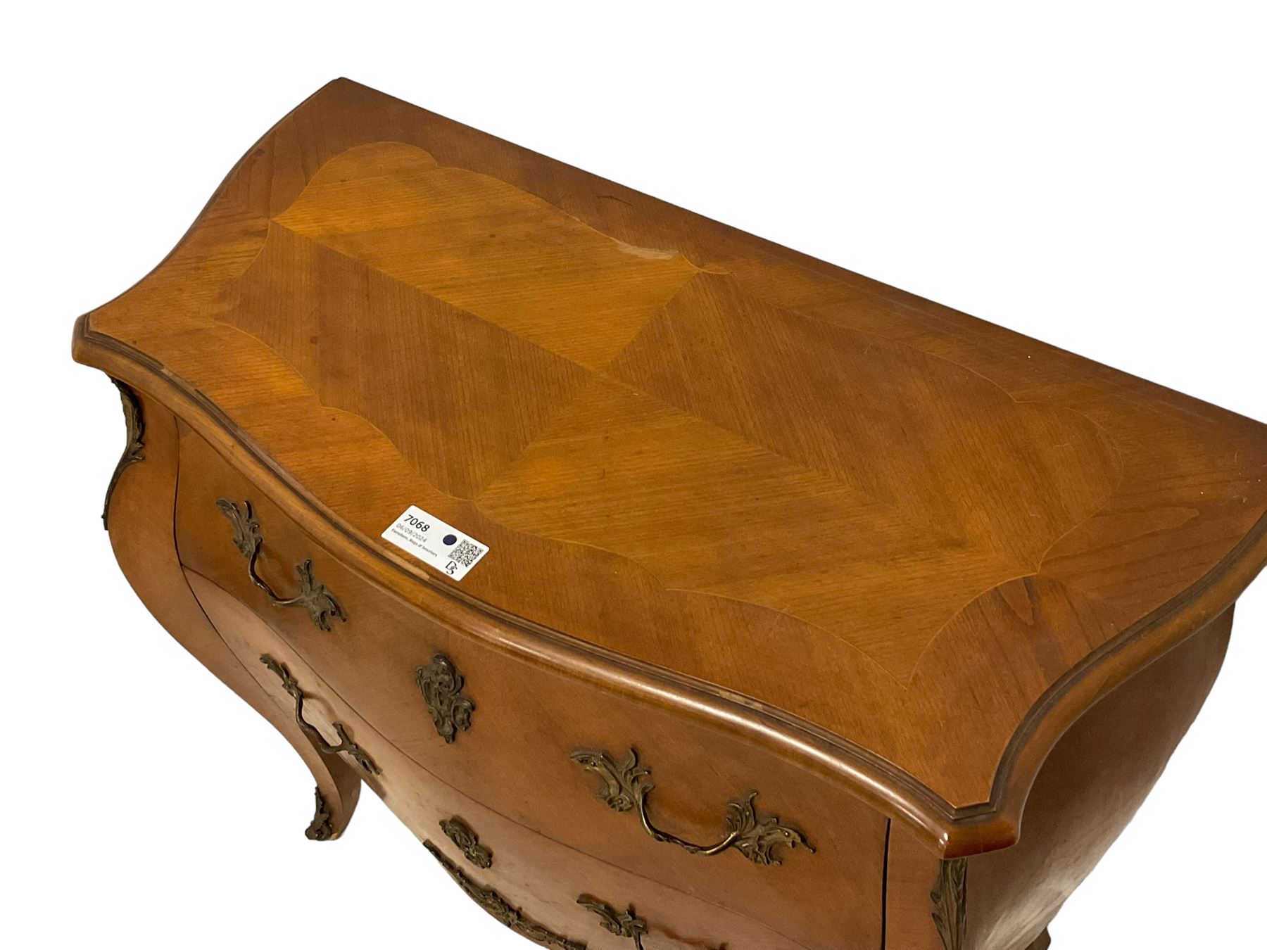 Late 20th century French design walnut bombe chest, shaped moulded top with quarter-matched veneers within crossbanding, fitted with two drawers with foliate cast metal handles and escutcheons, on tapering supports with ornate cast caps 