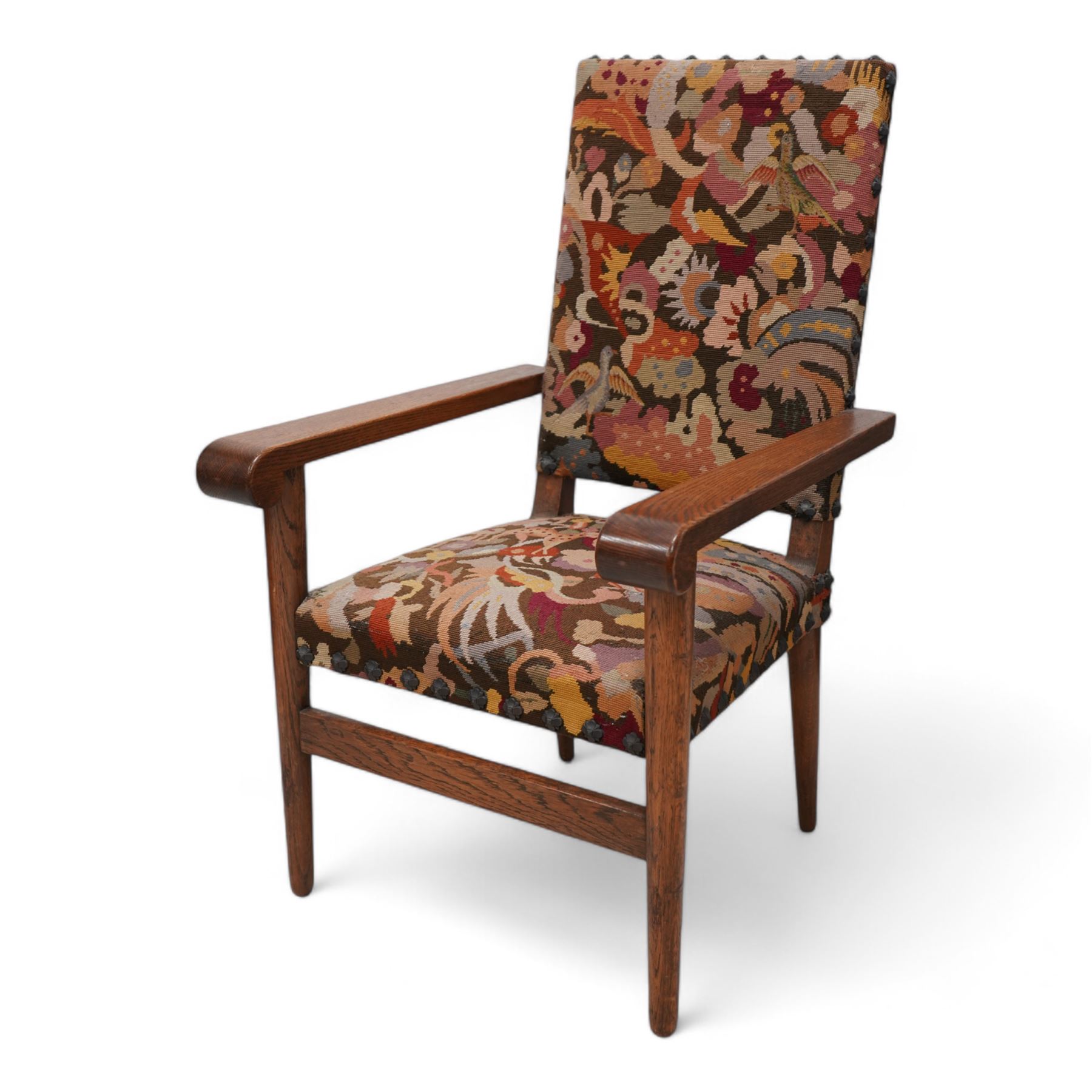 Arts & Crafts period oak framed open armchair, upholstered in needlework cover decorated with stylised floral motifs and birds, projecting arms with rolled terminals, on turned tapering supports united by plain stretcher 