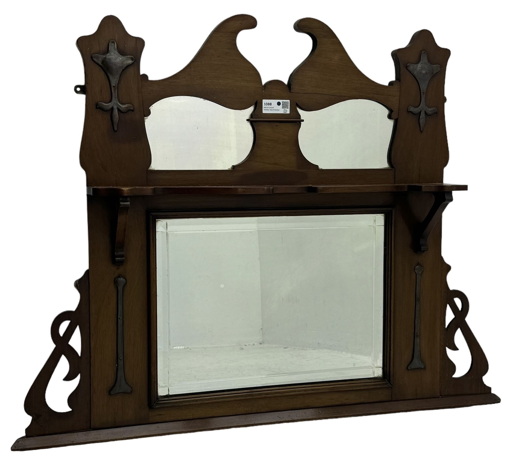 Arts & Crafts period walnut overmantel mirror, shaped pediment over shelf, rectangular bevelled mirror plate within applied mouldings, shaped and pierced corner brackets, decorated with shaped copper mounts 