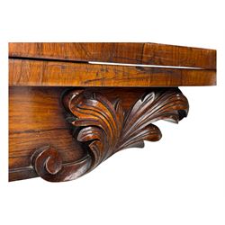 Early Victorian rosewood card table, rectangular foldover swivel top with rounded corners, red baize-lined surface, frieze adorned with carved foliate motifs, supported by a central octagonal waisted column on shaped quatrefoil base, terminating in scrolled feet with concealed metal castors