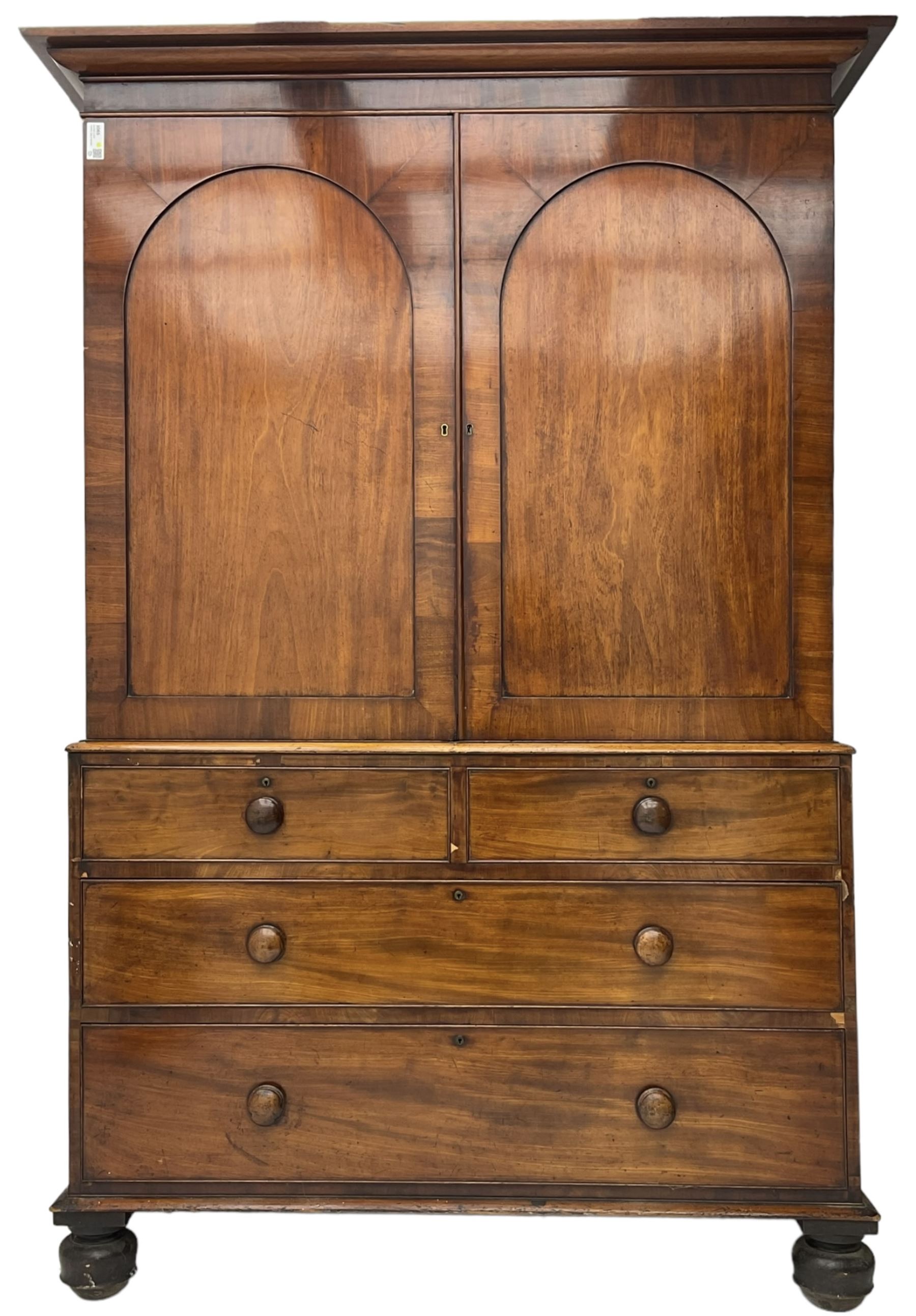 Victorian figured mahogany linen-press, projecting moulded cornice over two arch panelled doors, fitted with two short and two long cock-beaded drawers, on turned feet