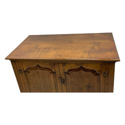 Oak drinks or media cabinet, projecting moulded cornice over two Gothic arch panelled doors on sliding tracks enclosing open storage, two drawers with brass drop handles, on bracket supports