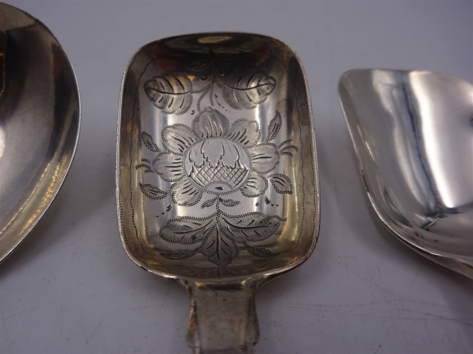 Three silver caddy spoons, comprising George III Fiddle pattern example, William IV Fiddle pattern example with later engraved bowl. and shovel example with twist handle, hallmarked some elements indistinct