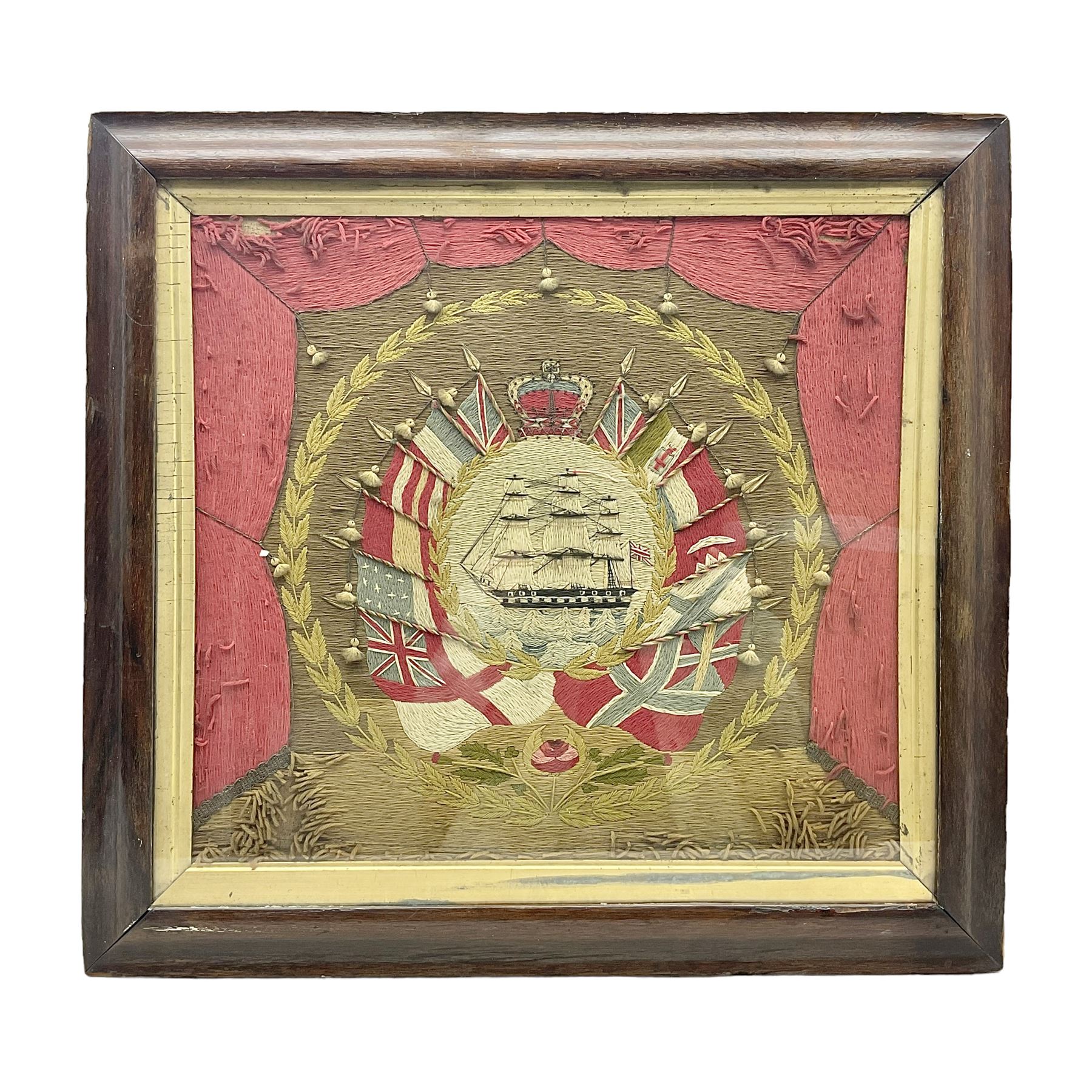 19th century woolwork, depicting a clipper ship, fully rigged over black hull with white ports, within a border of ensigns and flags and beaded crown above, in glazed wooden frame, H57cm