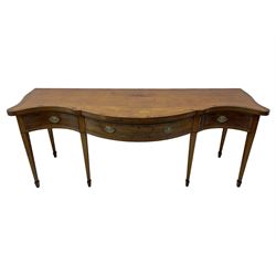 Large George III mahogany serpentine serving table, shaped top with crossing banding and stringing, the frieze fitted with three cock-beaded drawers, oval pressed brass handle plates decorated with urns, on square tapering supports with spade feet 