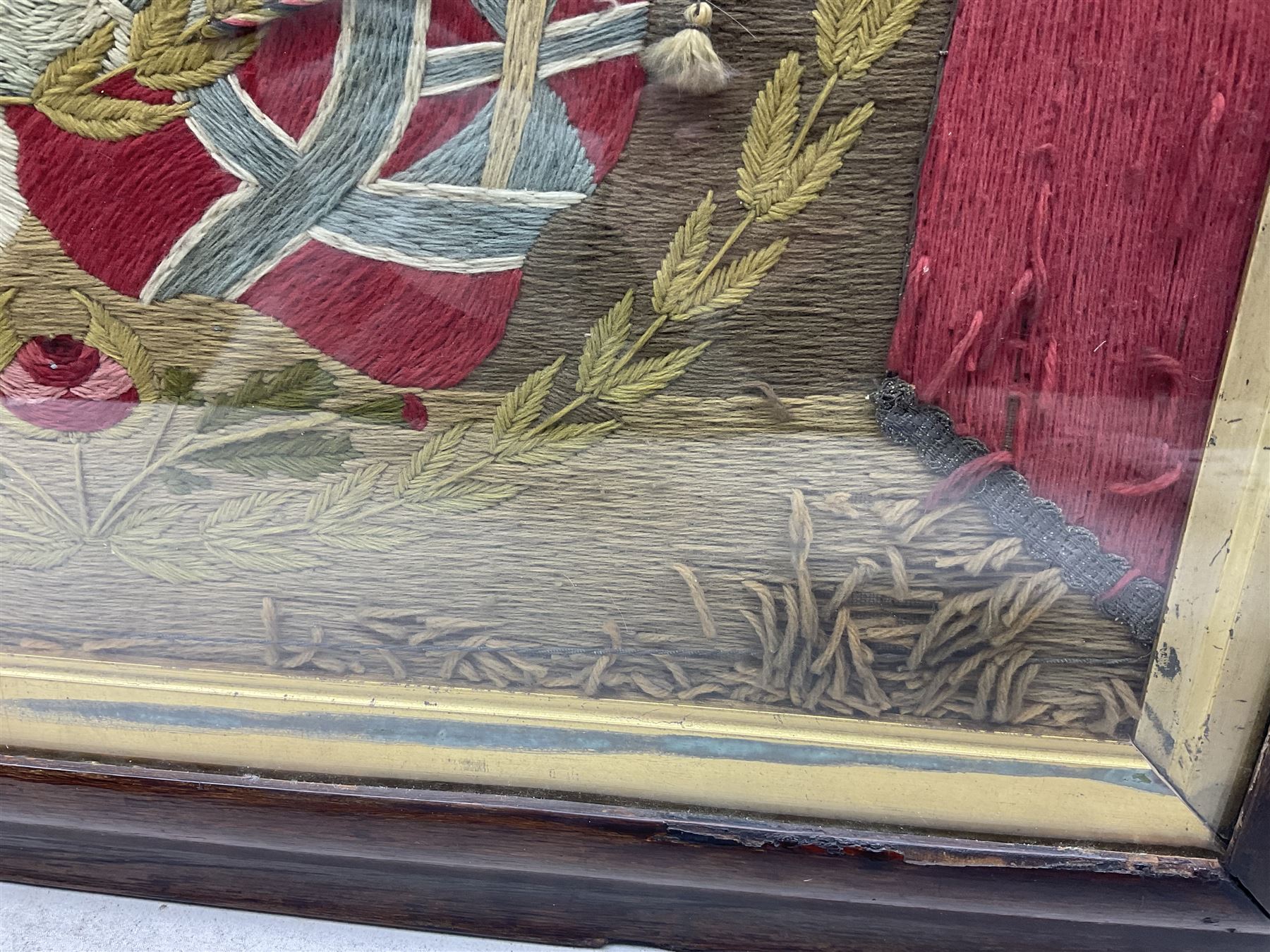 19th century woolwork, depicting a clipper ship, fully rigged over black hull with white ports, within a border of ensigns and flags and beaded crown above, in glazed wooden frame, H57cm