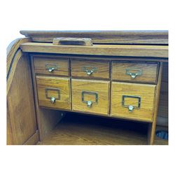 Early 20th century oak tambour roll-top desk, the top with fitted interior including drawers, pigeonholes and compartments, the twin pedestals fitted with four drawers with carved handles, supported by plinth base 