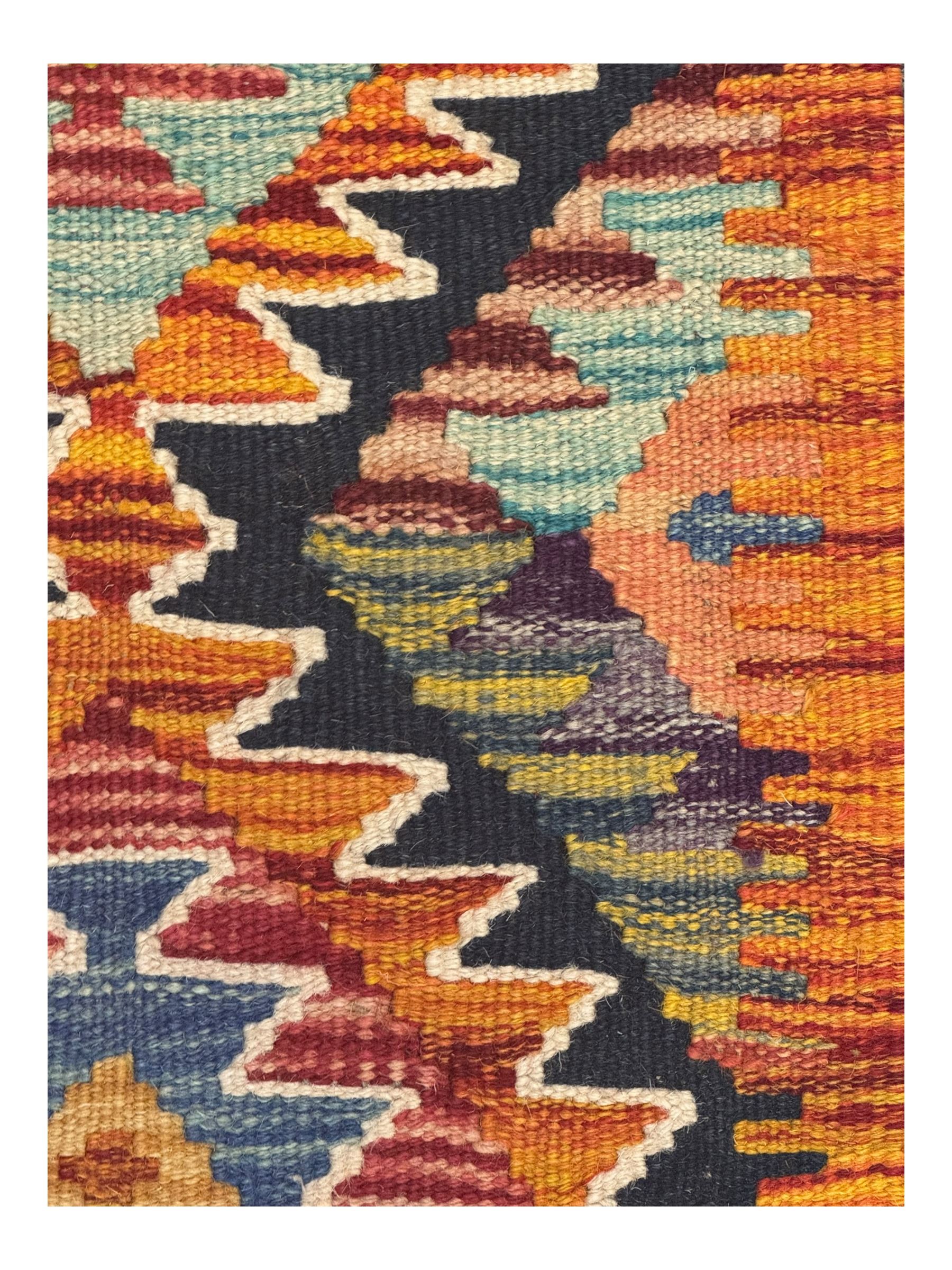 Chobi Kilim multicoloured ground runner, displaying diamond-shaped motifs in shades of blue, red, yellow, and green, accented by a bold black outline and bordered with a striped design, flatwoven with fringed edges