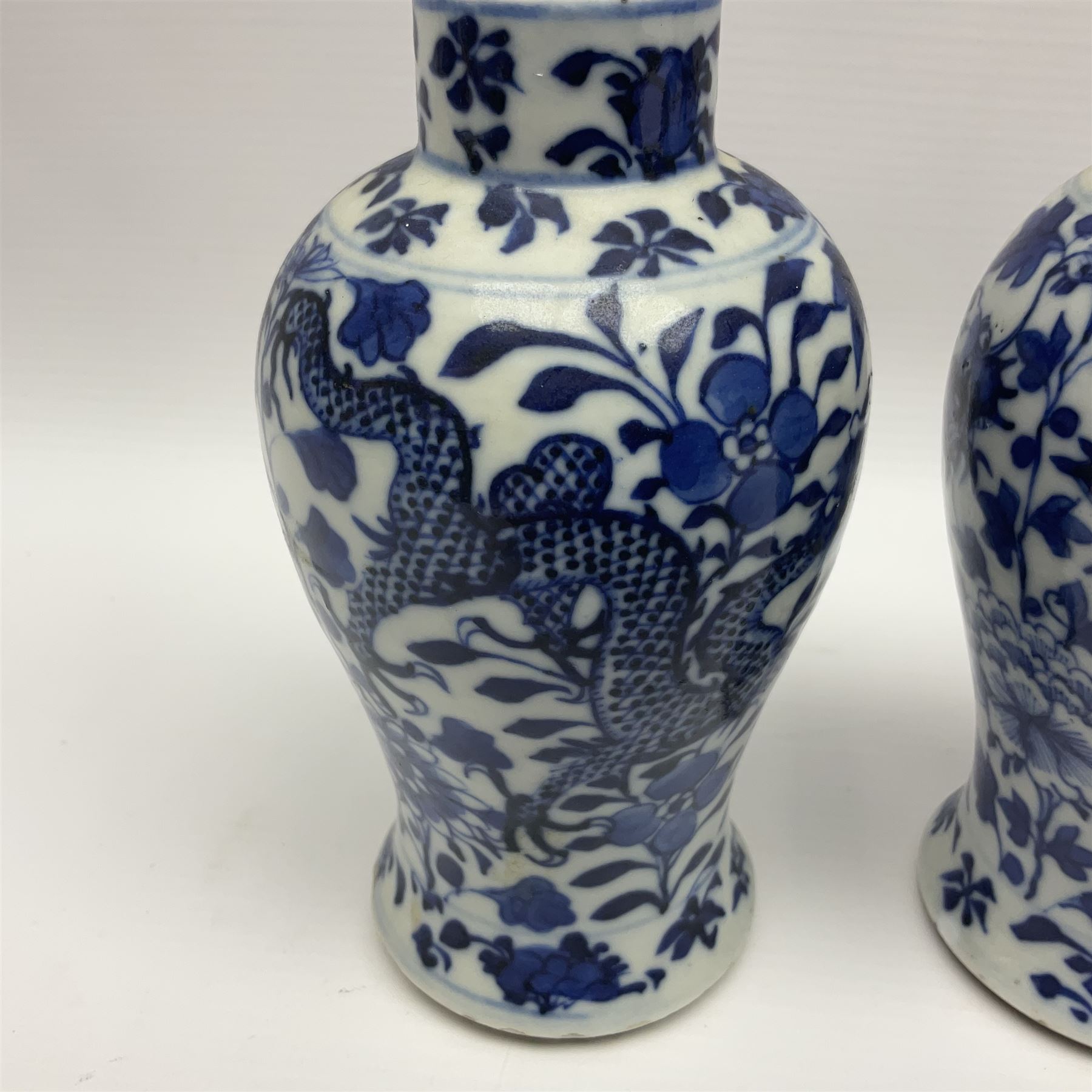 Pair of late 19th/early 20th century Chinese blue and white vases, each of baluster form, painted with dragons amidst flowers, each with Kangxi character marks beneath, H14cm 