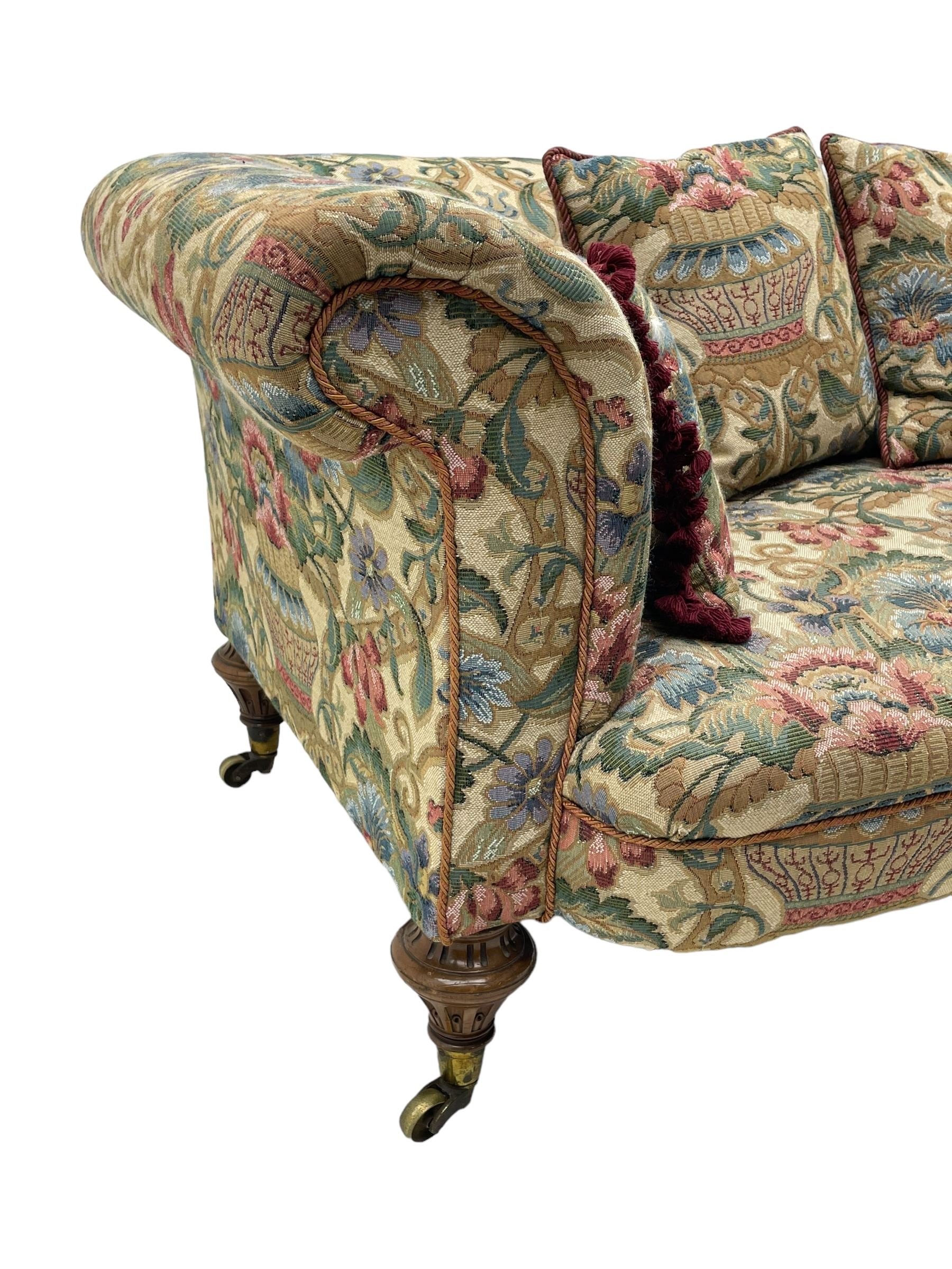 Mid-19th century walnut framed two-seat sofa, rolled arms over sprung seat, single drop-end action, raised on turned and fluted feet with brass cups and castors, upholstered by E & S Gott in traditional floral pattern fabric decorated with urns