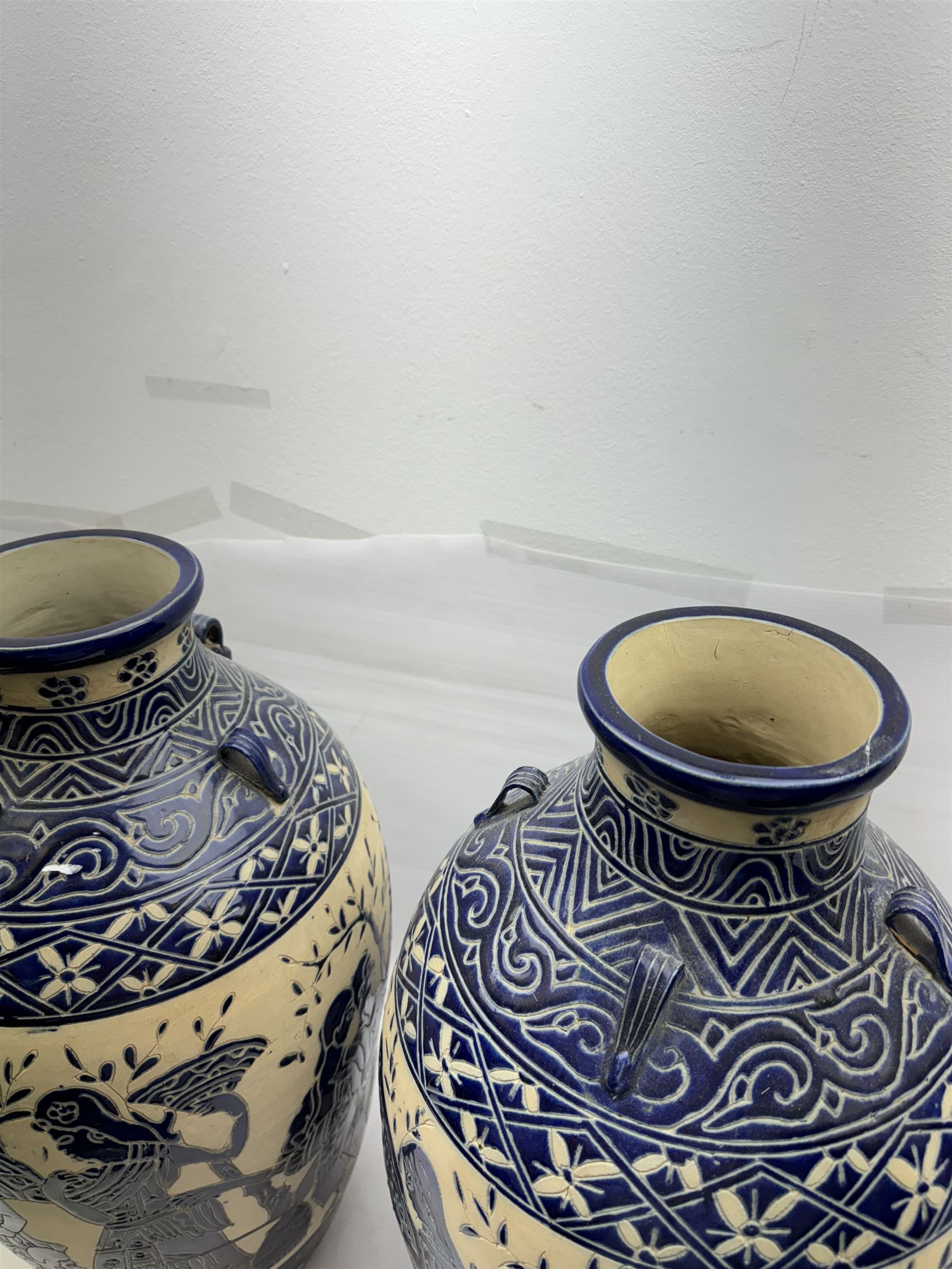 Pair of blue and white Cretan style vases, decorated with figures among trees with blue boarders on a white ground, H55cm