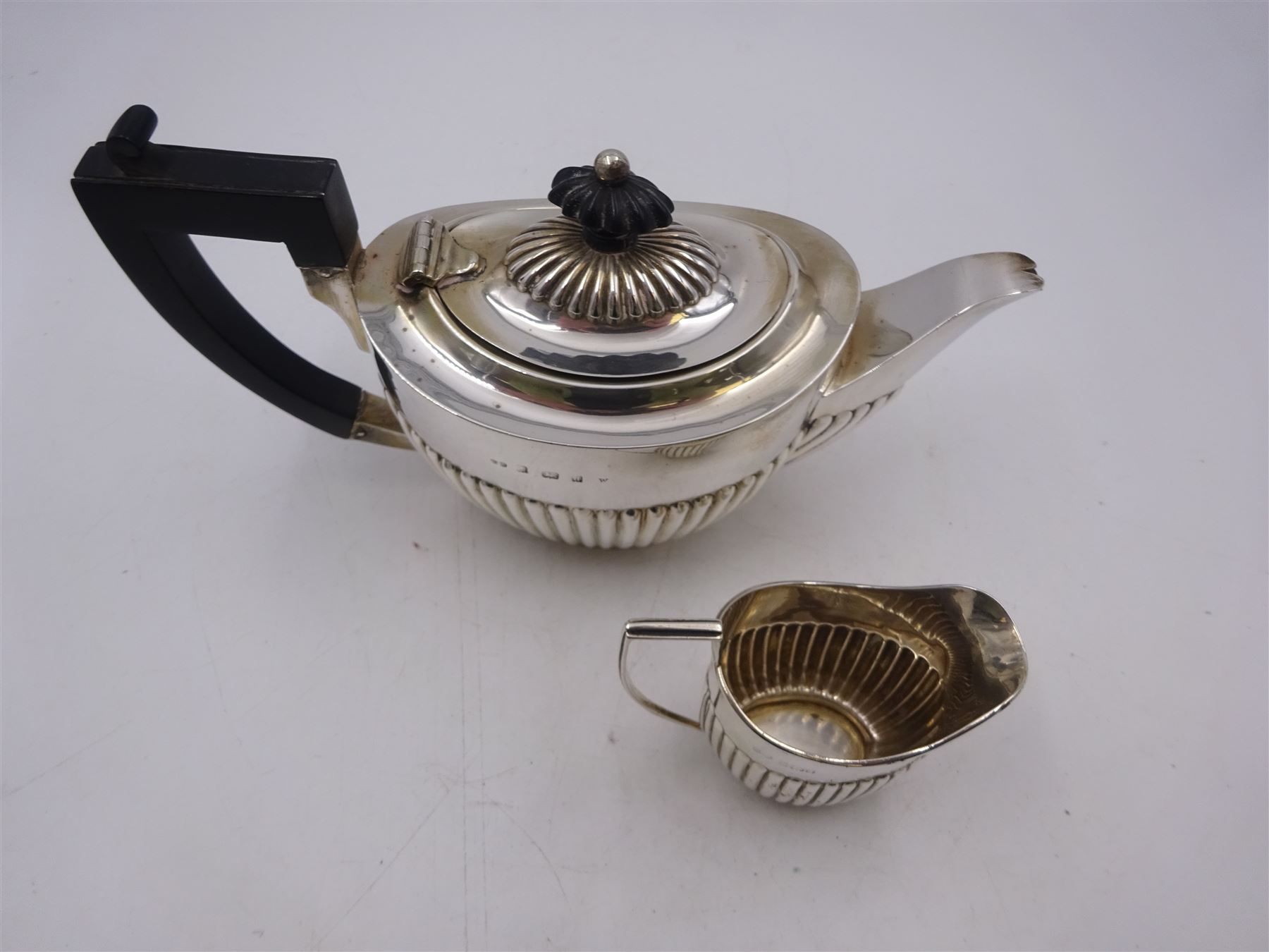 Edwardian silver bachelor's two piece tea set, comprising teapot and milk jug, each of oval part fluted form, the teapot black plastic handle and finial, hallmarked Synyer & Beddoes, Birmingham 1903, teapot H10.5cm