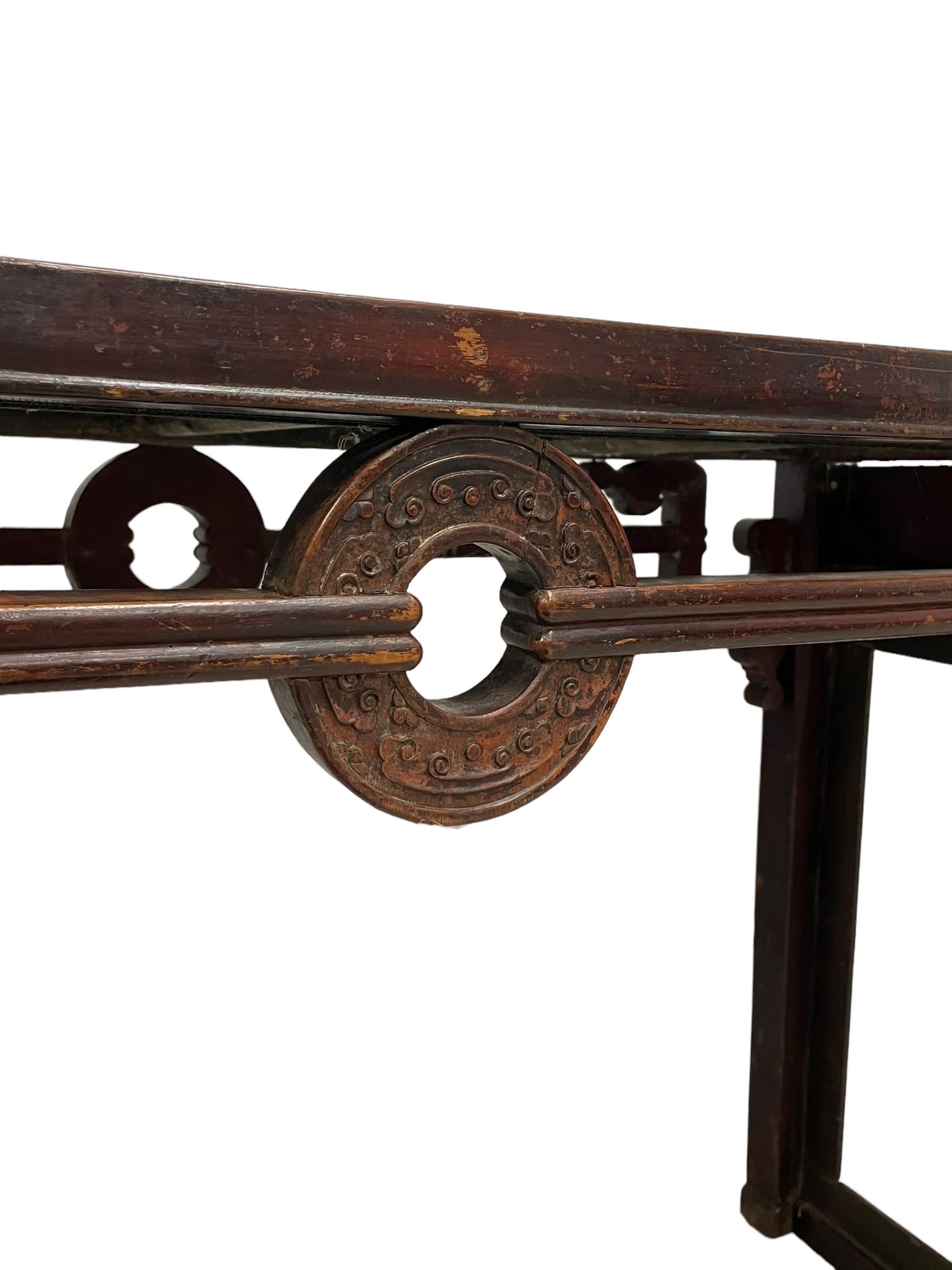 19th century Chinese lacquered hardwood altar table, rectangular top with moulded edge, the pierced and carved frieze decorated with Chinese scroll symbols and a central circular roundel motif with raised scrolling carvings, on rectangular end supports