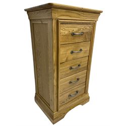 Contemporary light oak pedestal chest, moulded cornice and chamfered rectangular top with rounded fronts, over five drawers with metal handles and cock-beaded surrounds, on bracketed plinth base