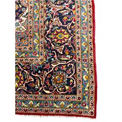 Persian Kashan crimson ground carpet, floral design central medallion surrounded by trailing leafy branches and stylised plant motifs, multi-band border with repeating floral design